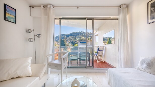 A modern hotel room with a balcony, a sofa, a bed, and a glass coffee table. - Apartment 'Sea and Sky 6 Personnes' with Mountain View, Private Terrace and Air Conditioning (Cannes)