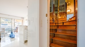 A modern interior with a staircase, a dining area with chairs and a table, and a view through a glass door. - Apartment 'Sea and Sky 6 Personnes' with Mountain View, Private Terrace and Air Conditioning (Cannes)