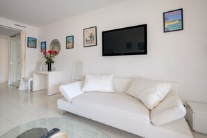 Ein modernes Wohnzimmer mit einem weißen Sofa, einem Flachbildfernseher und einem Glastisch.