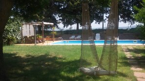 Un jardin avec une piscine, un hamac et une pergola.