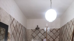 Une salle de bain avec une baignoire, deux toilettes, un lavabo et une douche avec un luminaire suspendu.
