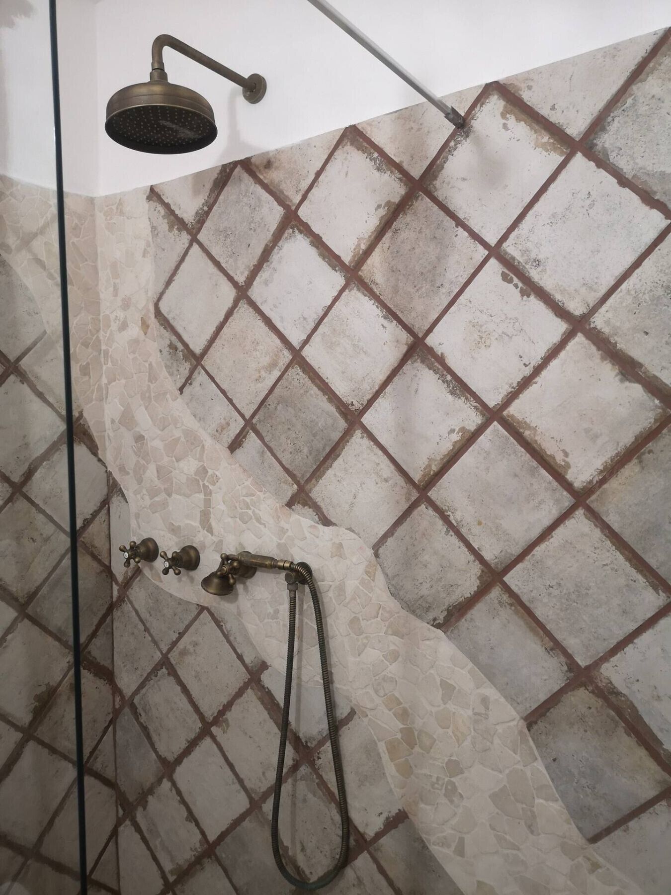 A shower with a handheld showerhead and a handheld hose.
