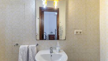 Un baño con un lavamanos blanco, un espejo y un perchero para toallas.