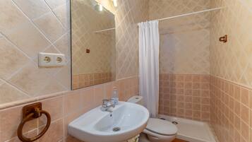 Een badkamer met een wastafel, toilet en douchehoek.