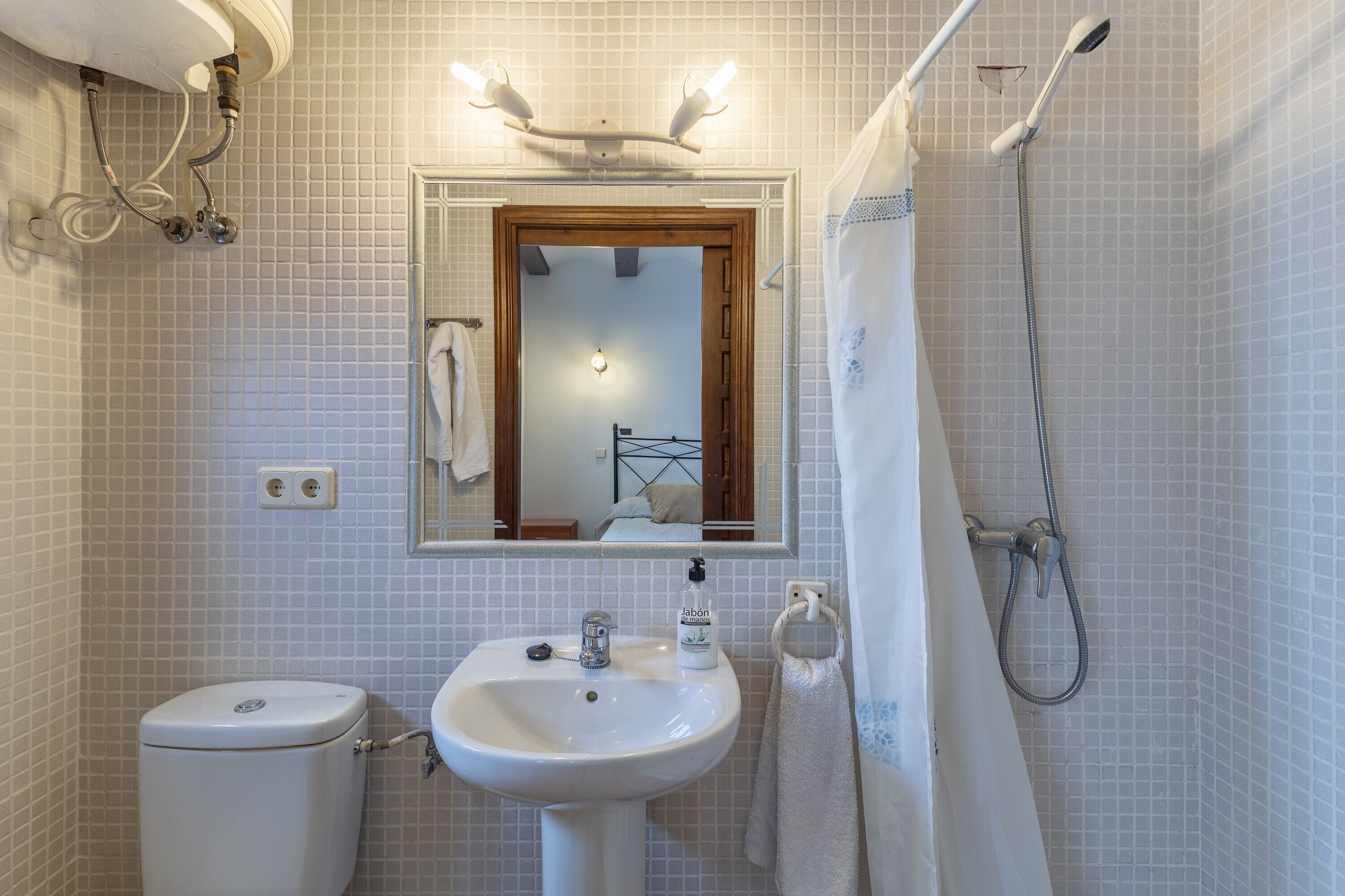 Un baño con lavamanos, inodoro y ducha blancos.