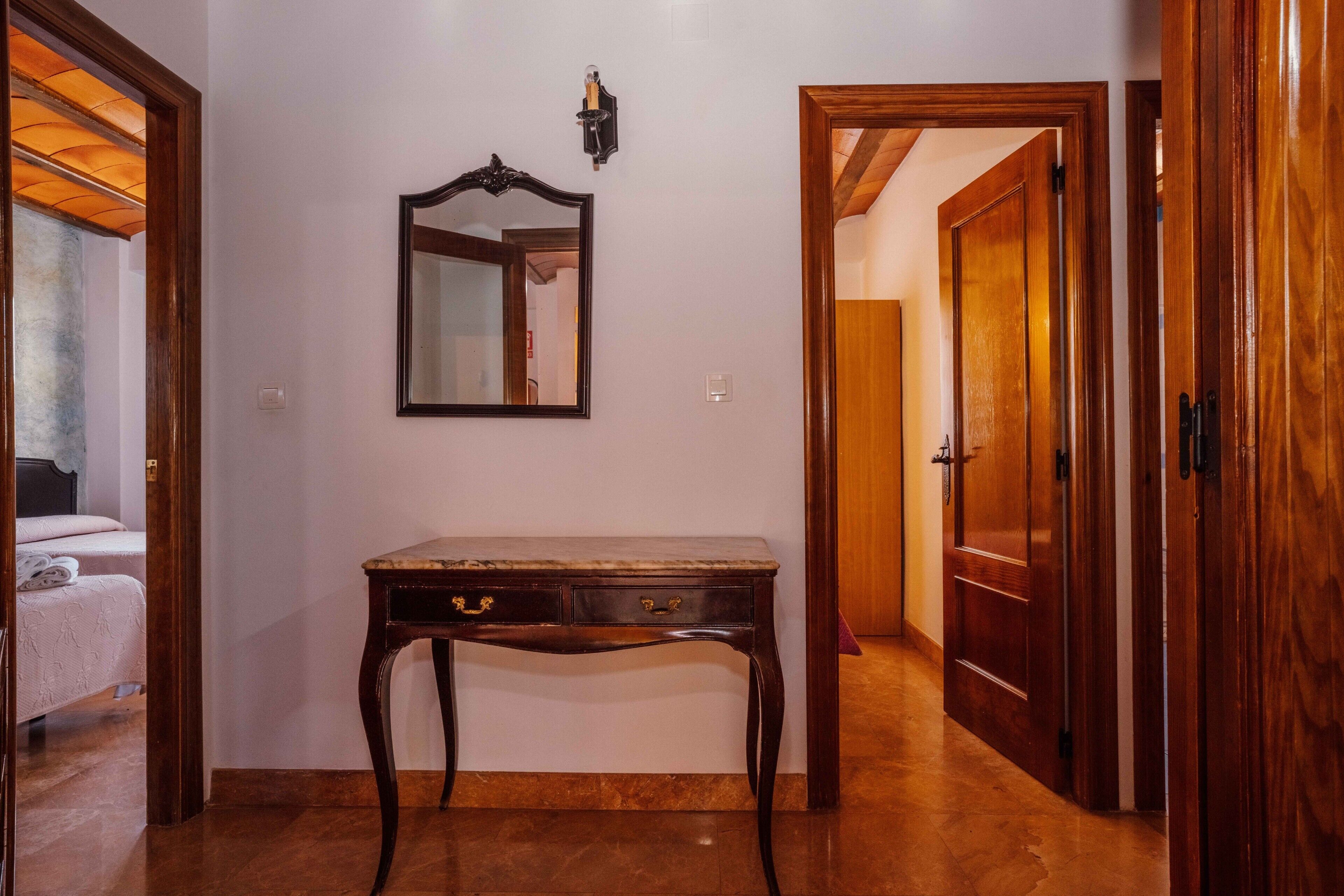 Une pièce avec un bureau en bois, un miroir et une porte donnant sur une autre pièce.