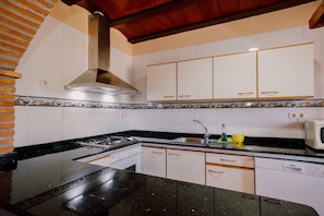 A kitchen with white cabinets, a black countertop, a stainless steel range hood, a microwave, and a dishwasher.