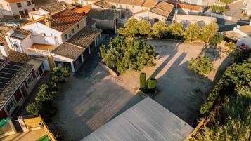 Vista aérea de una zona residencial con edificios de tejas de terracota, un patio empedrado y zonas verdes.