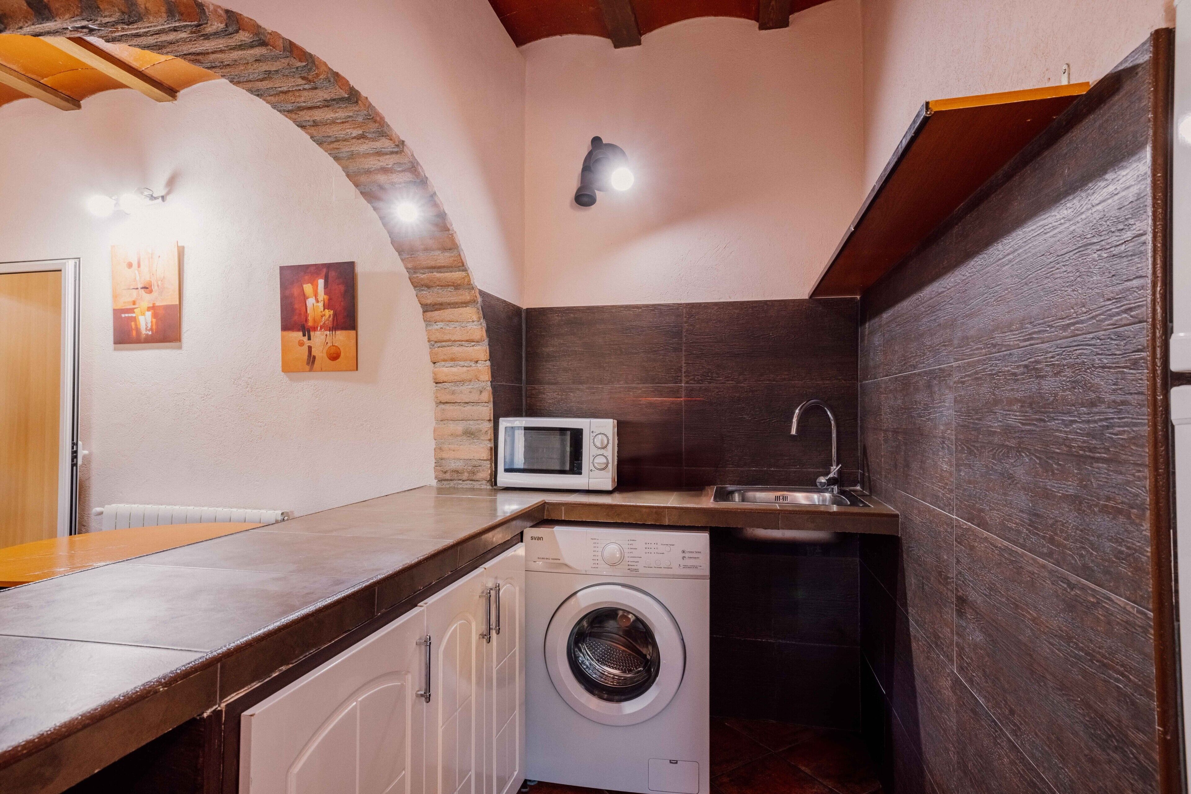 Una cocina compacta con lavadora, microondas y fregadero.