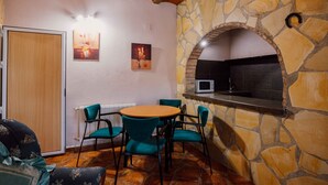 A dining area with a stone wall, a round table, teal chairs, and a wooden ceiling. - Country House 'Casa Dolores' with Mountain View, Wi-Fi and Air Conditioning (Caravaca De La Cruz)