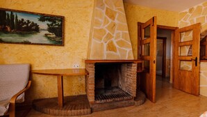 A room with a fireplace, a painting on the wall, a wooden door, and a chair.