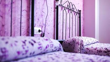 A bed with a patterned cover, a metal headboard, and a power outlet on the wall.