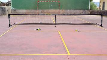 Een tennisbaan buiten met een net, een bal en een racket.