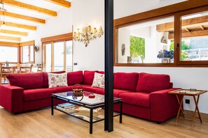 A red sofa, a glass-top coffee table, wooden beams, and a large window with a view. - Rural House 'Casa Rural El Trillo' with Private Pool, Private Terrace and Wi-Fi (Aldea del Obispo (Salamanca))
