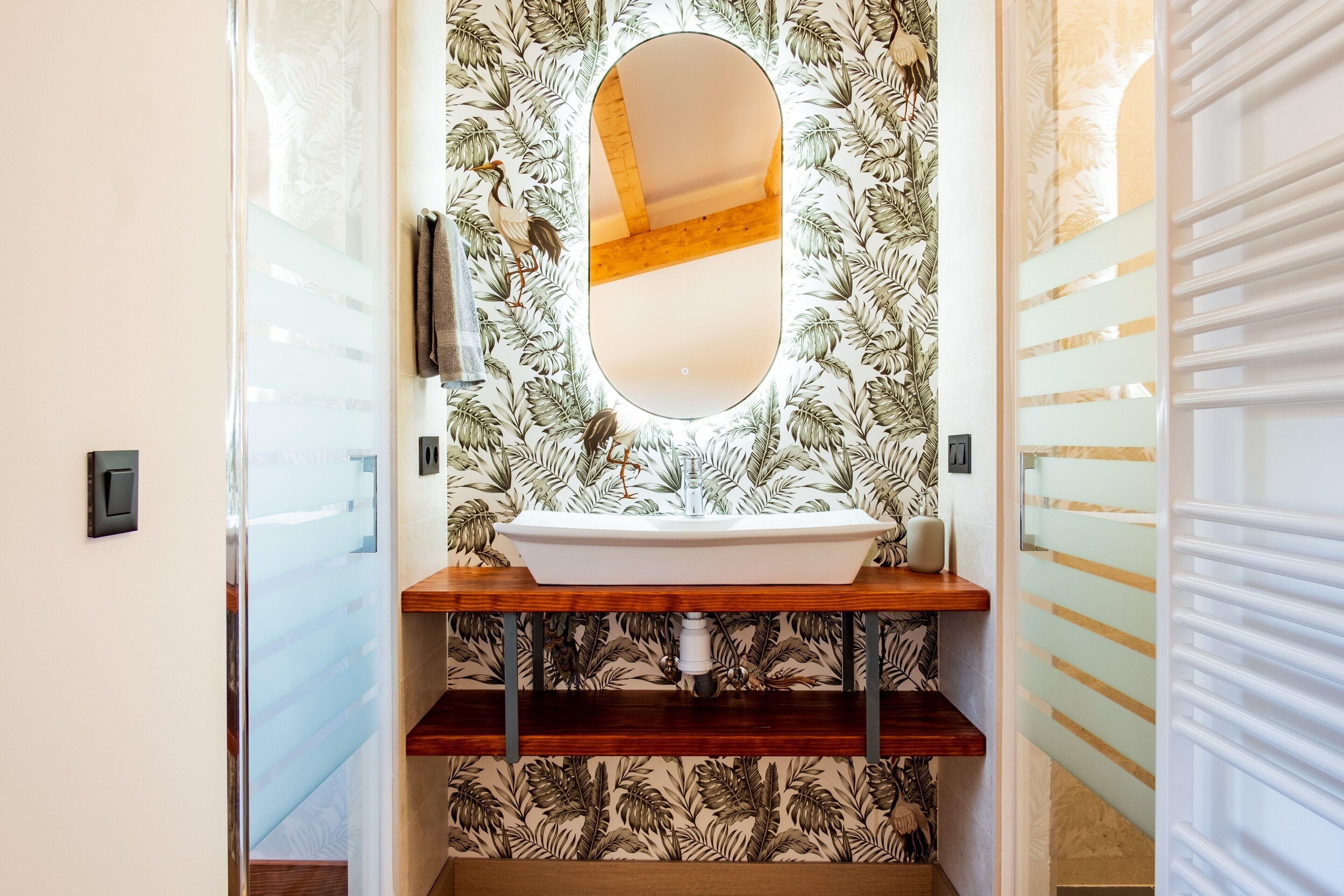 A bathroom with a wooden vanity, a white sink, and a mirror.
