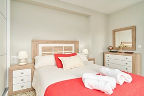 Un dormitorio con cama, mesitas de noche, cómoda y espejo.