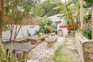 Un patio al aire libre con bancos de piedra, una parrilla y diversas plantas.
