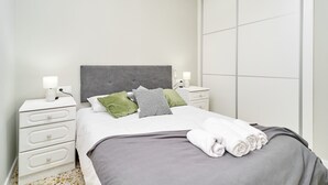 A neatly made bed with pillows, a bedside table with a lamp, and a large wardrobe.