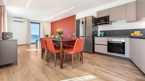 A modern kitchen with a dining area, featuring a large window, built-in appliances, and a view of the outdoors. - Holiday Apartment "Il Cinque" with Lake View, Shared Pool & Wi-Fi (Tignale)