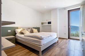 Een moderne slaapkamer met een bed, nachtkastjes, een raam met uitzicht en ingebouwde planken.