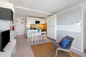 A modern kitchen with white cabinets, a microwave, and a dining area with a table and chairs. - Studio Apartment 'Estúdio Moderno' with Sea View, Wi-Fi and Air Conditioning (Albufeira)