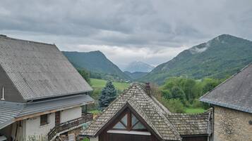 Een klassiek chalet met een schuin dak, een houten balkon en een stenen muur.