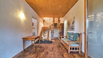 Een kamer met een houten plafond, een trap, een bank en een tafel.