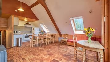 A cozy kitchen with wooden beams, a dining area with hexagonal patterned flooring, and a window with a view.