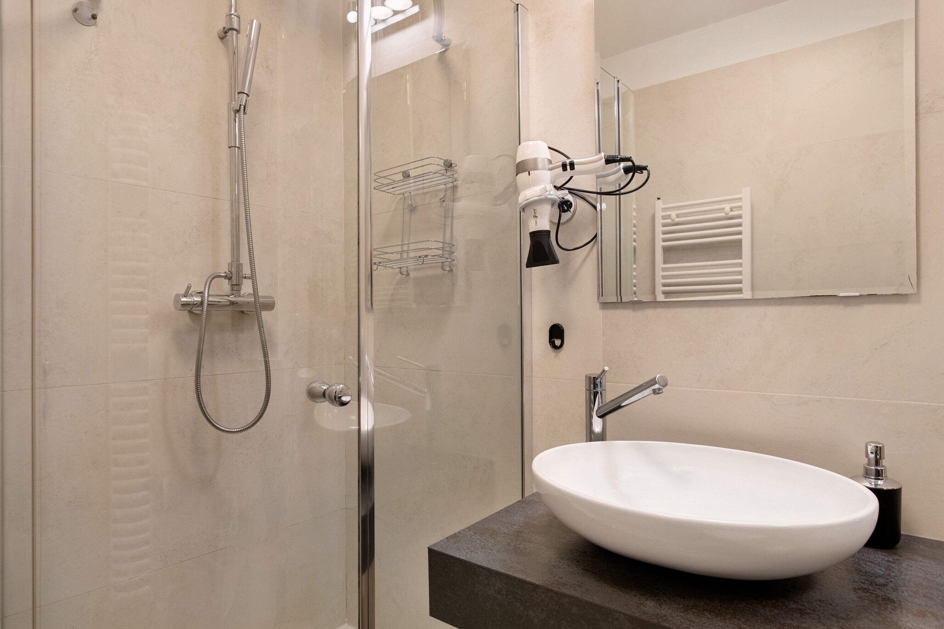 Un baño moderno con cabina de ducha de vidrio, un lavabo blanco y un perchero para toallas.