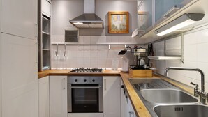 A modern kitchen with white cabinets, a stainless steel sink, a gas stove, and a built-in oven.