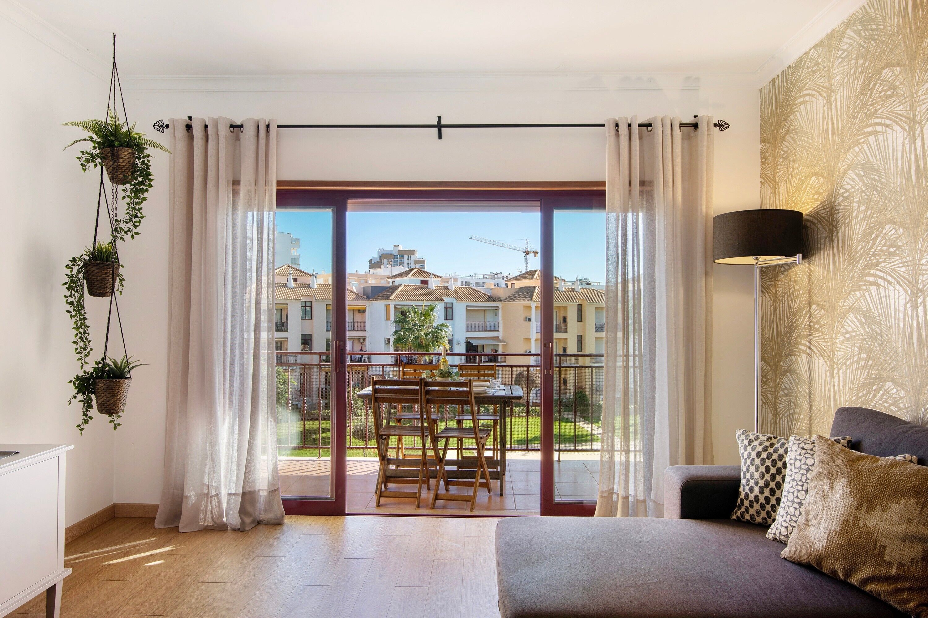 A modern apartment with a balcony, a dining area, and a sofa with decorative pillows.
