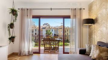 A modern apartment with a balcony, a dining area, and a sofa with decorative pillows.