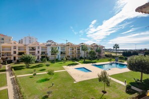 A hotel with multiple balconies, a swimming pool, and a well-maintained lawn.