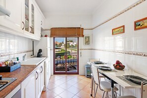 Una cocina con alacenas blancas, una barra de café y un comedor con sillas y una mesa.