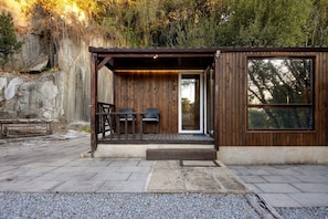 A wooden cabin with a porch, a table, and chairs.