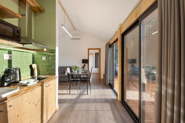 A modern kitchen with wooden cabinets, a green backsplash, and a dining area with a table and chairs.