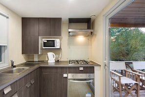 A compact kitchen with a microwave, gas stove, and a coffee maker.