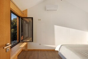 Camera da letto con una grande finestra, un letto e un condizionatore d'aria.
