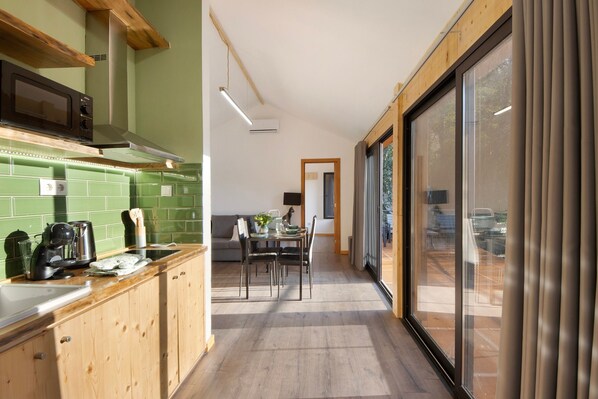 Una cucina moderna con mobili in legno, zoccolo verde e zona pranzo con tavolo e sedie.