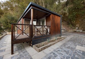 Une cabane en bois dotée d’un balcon, d’un chemin en pierre et entourée d’arbres.