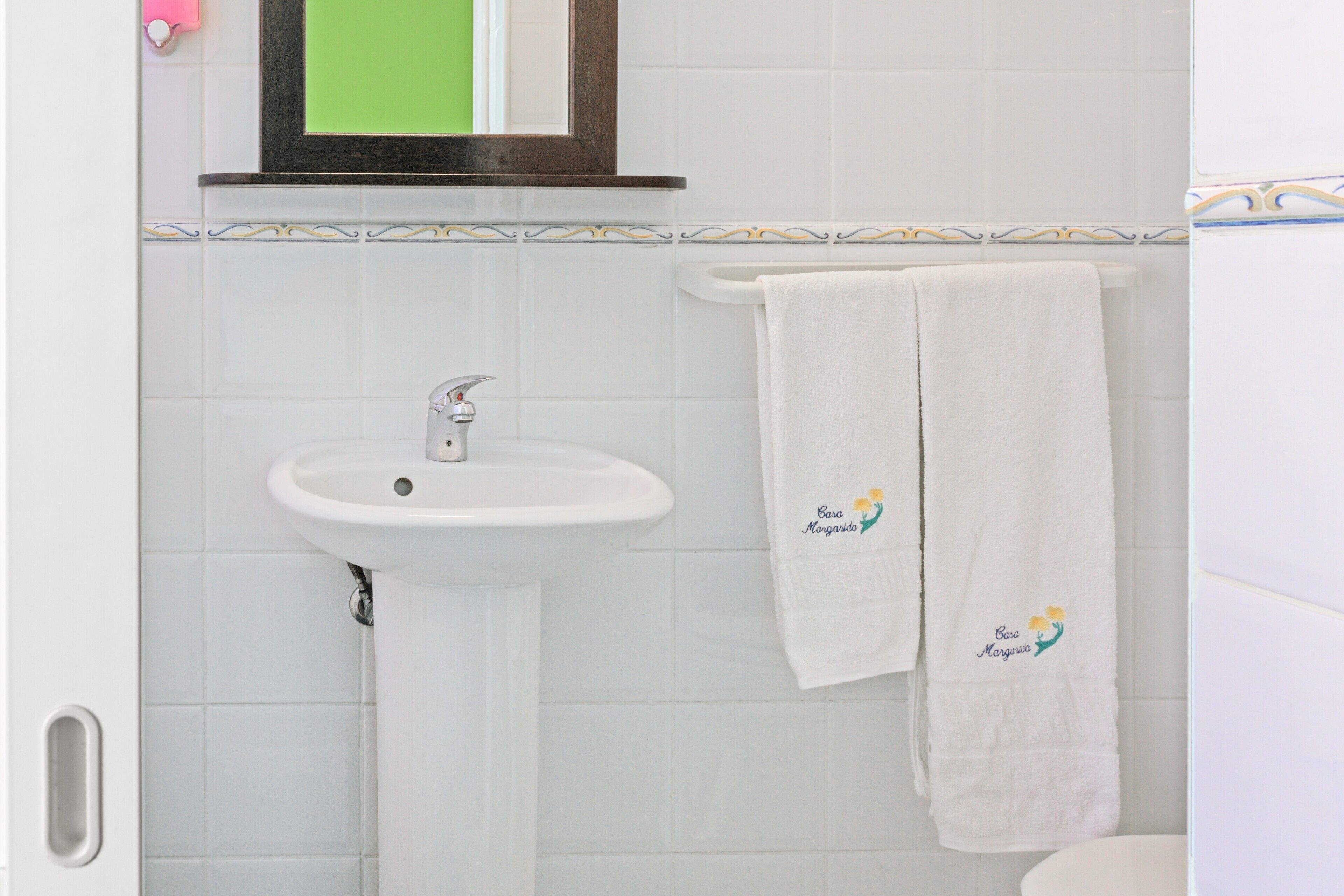 A bathroom with a white sink, a mirror, and a towel with a logo.