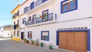 A multi-story building with balconies, potted plants, and a cobblestone street.