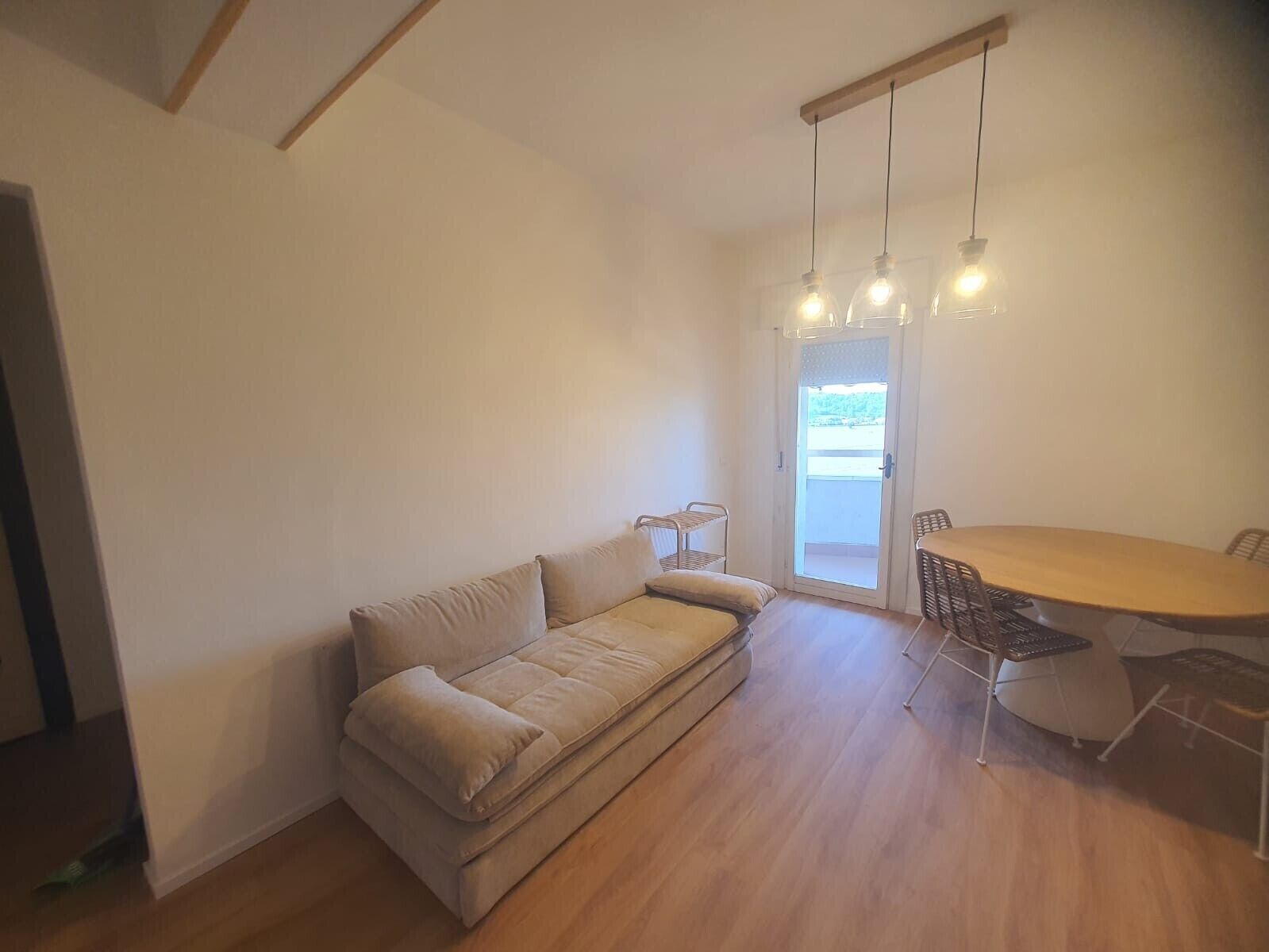 A room with a sofa, a dining table with chairs, and a door leading outside.
