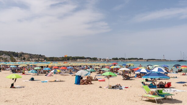 A crowded beach with numerous colorful umbrellas and beach chairs.