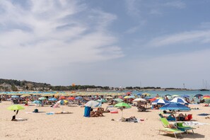 Una playa concurrida, con numerosos paraguas y sillas de playa de colores.