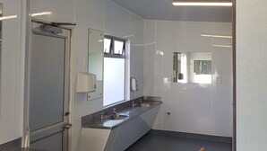 Une salle de bain moderne avec un grand miroir, deux lavabos et un espace douche.