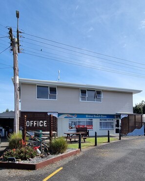 A two-story building with a sign for an office and a Urenui Beach Store. - Urenui Beach Camp (Urenui)