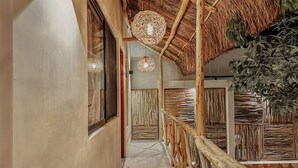 A corridor with a thatched ceiling, wooden railings, and woven wall panels. - "Lotus" Tulum Jungle Suite | Fast Wifi | Private Balcony (Tulum)