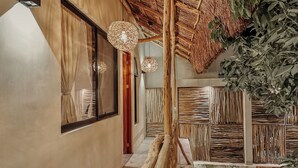 A hallway with a thatched ceiling, woven light fixtures, and a wooden wall panel. - "Lotus" Tulum Jungle Suite | Fast Wifi | Private Balcony (Tulum)