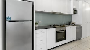 Una cocina moderna con armarios blancos, un refrigerador de acero inoxidable, un microondas, una estufa y un lavavajillas.